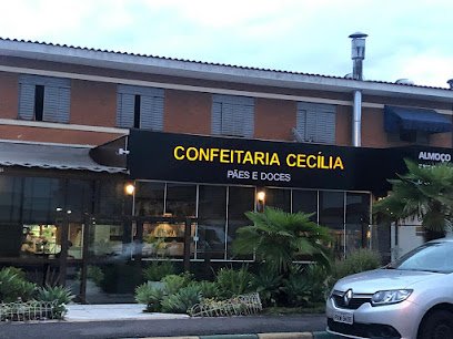 Fachada da Confeitaria Cecília, com letreiro preto e amarelo e jardim na entrada